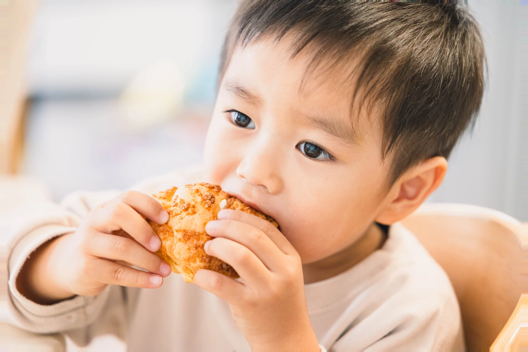 パンをおいしそうにかじる幼い男の子のアップ